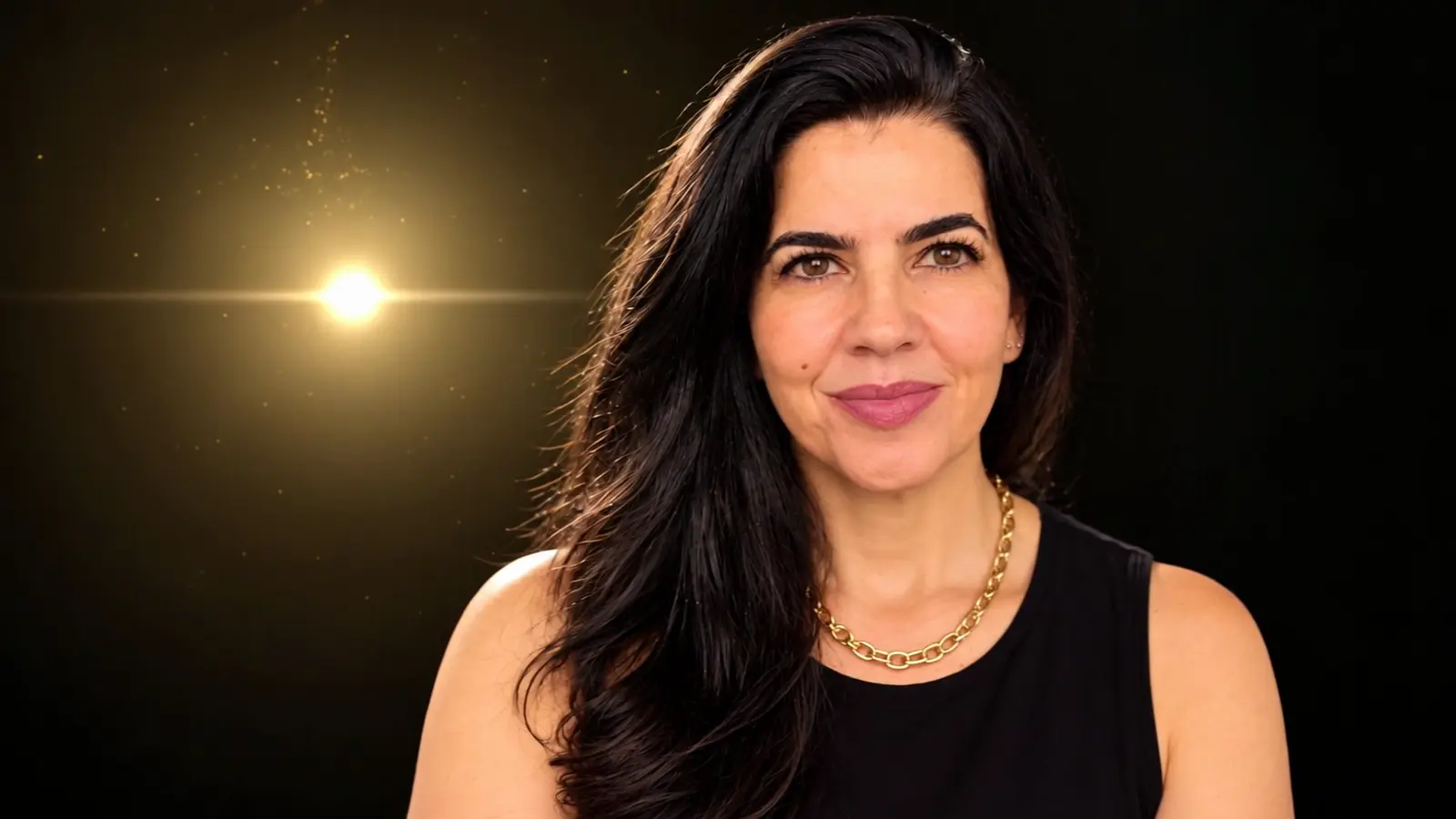 Luciana Carvalho olhando para a câmera com uma expressão serena e um leve sorriso; ao lado dela brilha uma luz dourada.